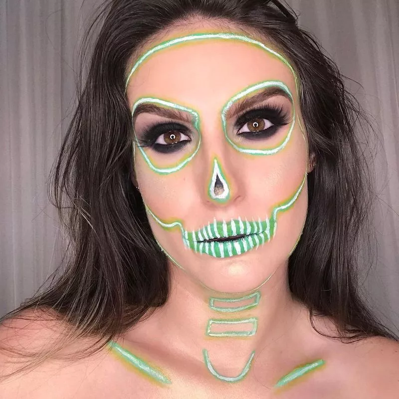 Makeup artist wears neon green skull makeup look