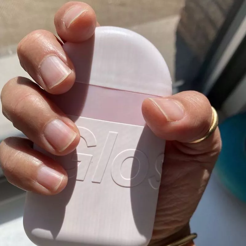 Hand with clean, buffed nails holding Glossier Hand Cream