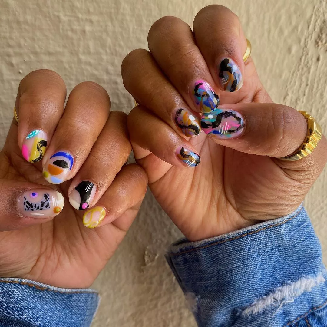 Person's nails painted with colorful abstract art designs.