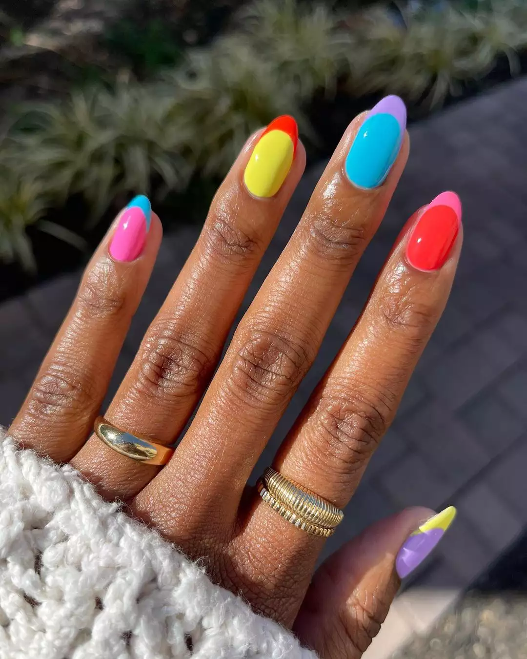 Person's hand with color-blocked French tip nail art. 