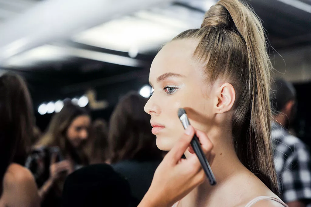 Girl getting makeup done before runway show