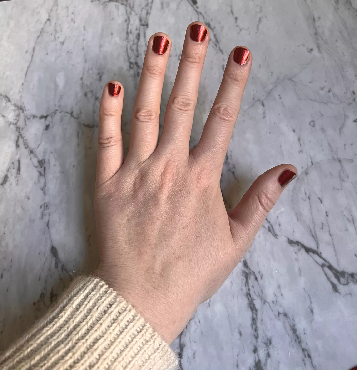 photo of hand with red nail wraps applied to shorter fingernails