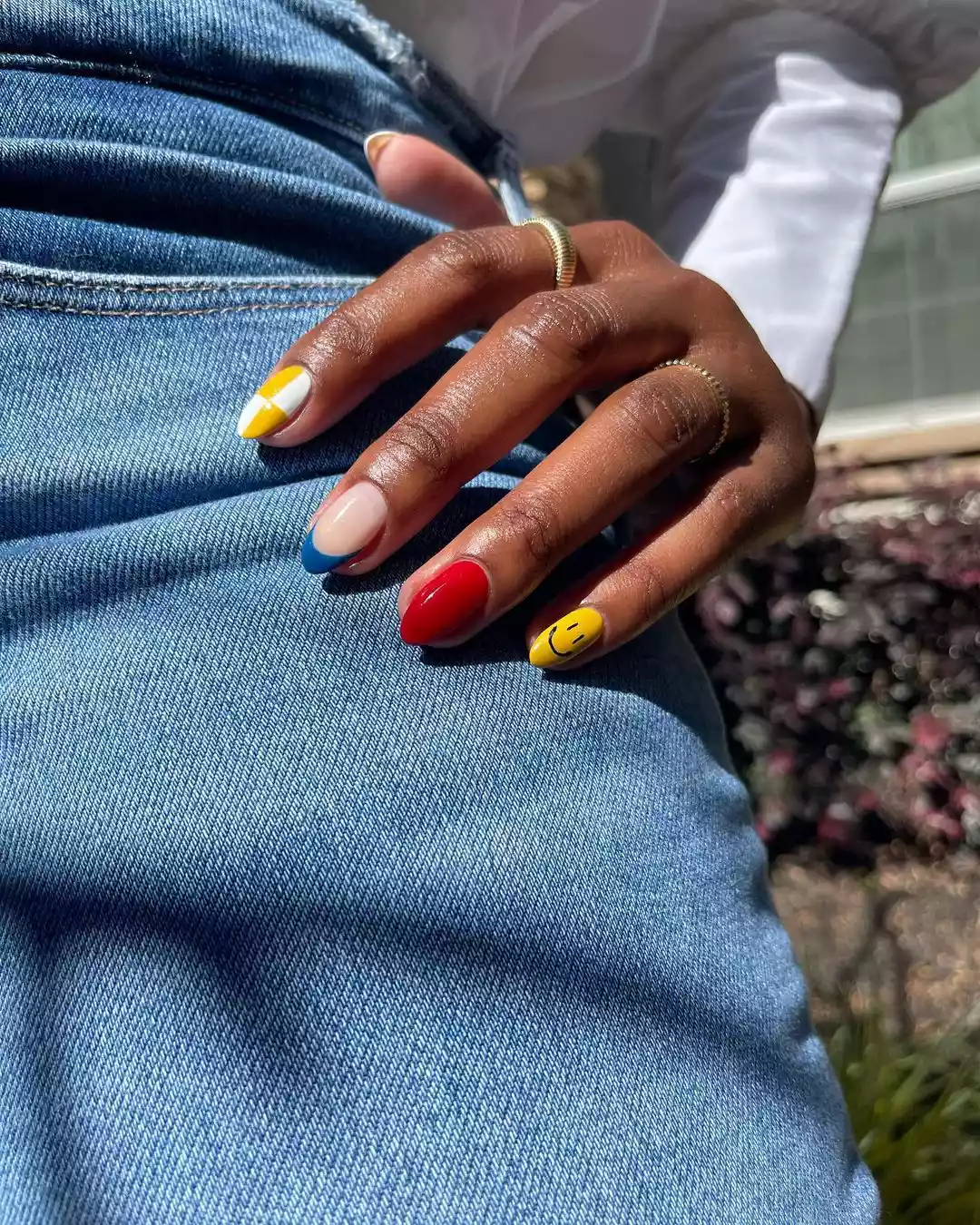 Black person's hand with mismatched nail art. 