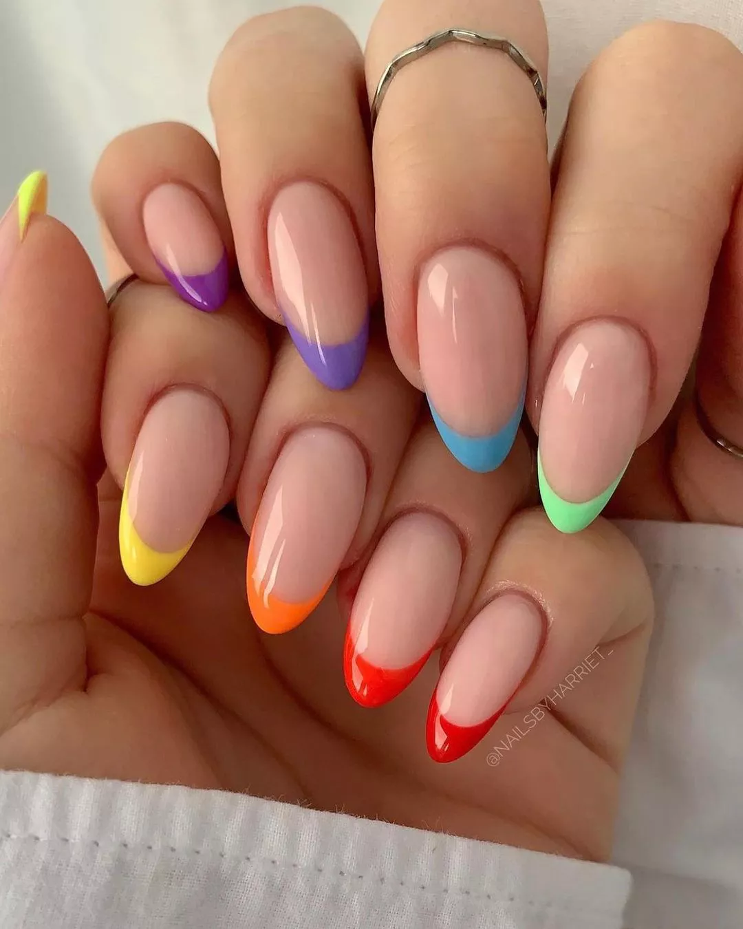 Hands with rainbow French tip nails. 