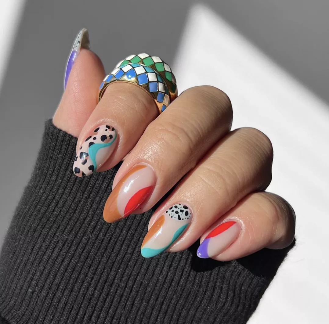 Person's nails painted with cheetah and dalmatian print, and swirls of different colors. 