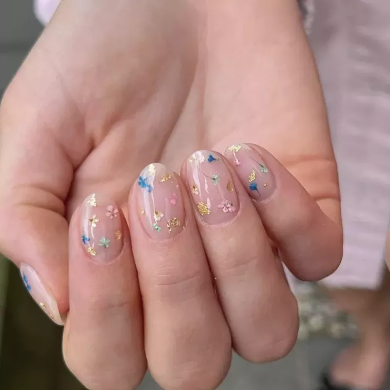 Milk bath nails with blue, gold, pink, and green flowers
