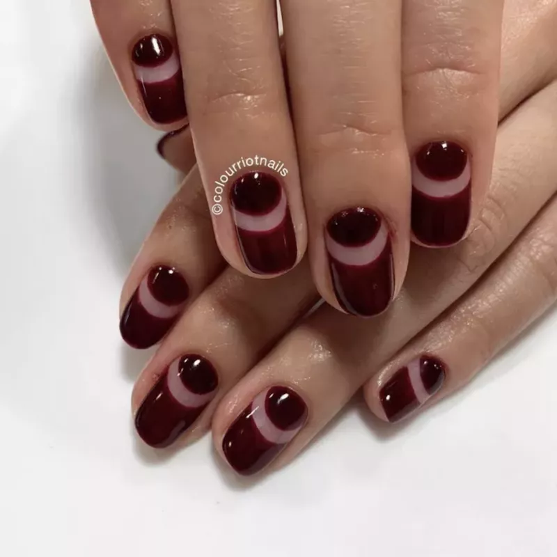 Wine-colored manicure with negative space half moon stripe
