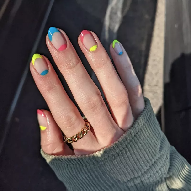 Neon yellow, blue, and pink French manicure with half-moon design