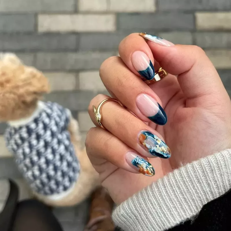 French manicure with dark blue tips and blue and brown marbled accent nails