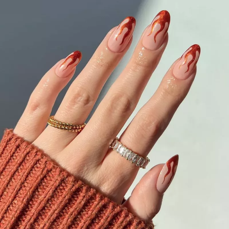 Hand with burnt orange flaming tips manicure