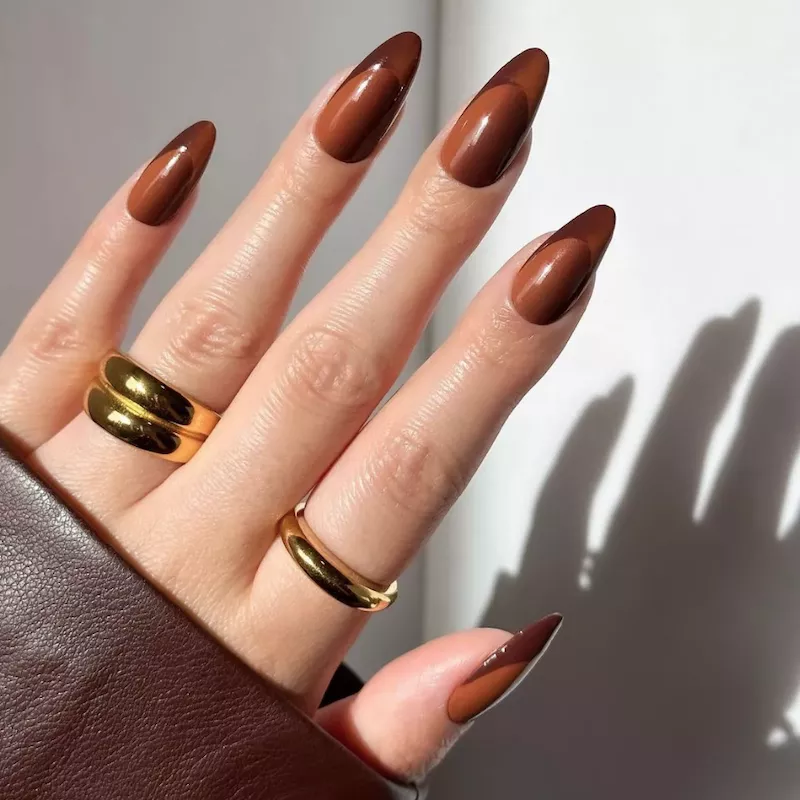 Hand with two-toned brown French manicure and gold rings