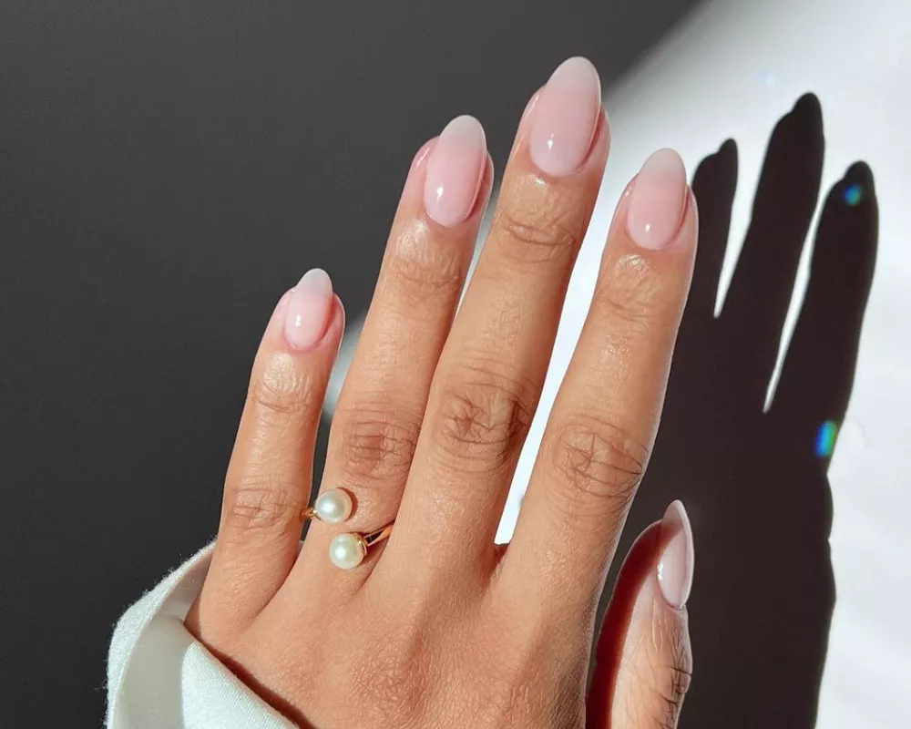 Hand with pale pink manicure and pearl open ring