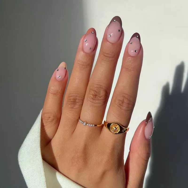 French manicure with different neutral-colored tips and rhinestones on top