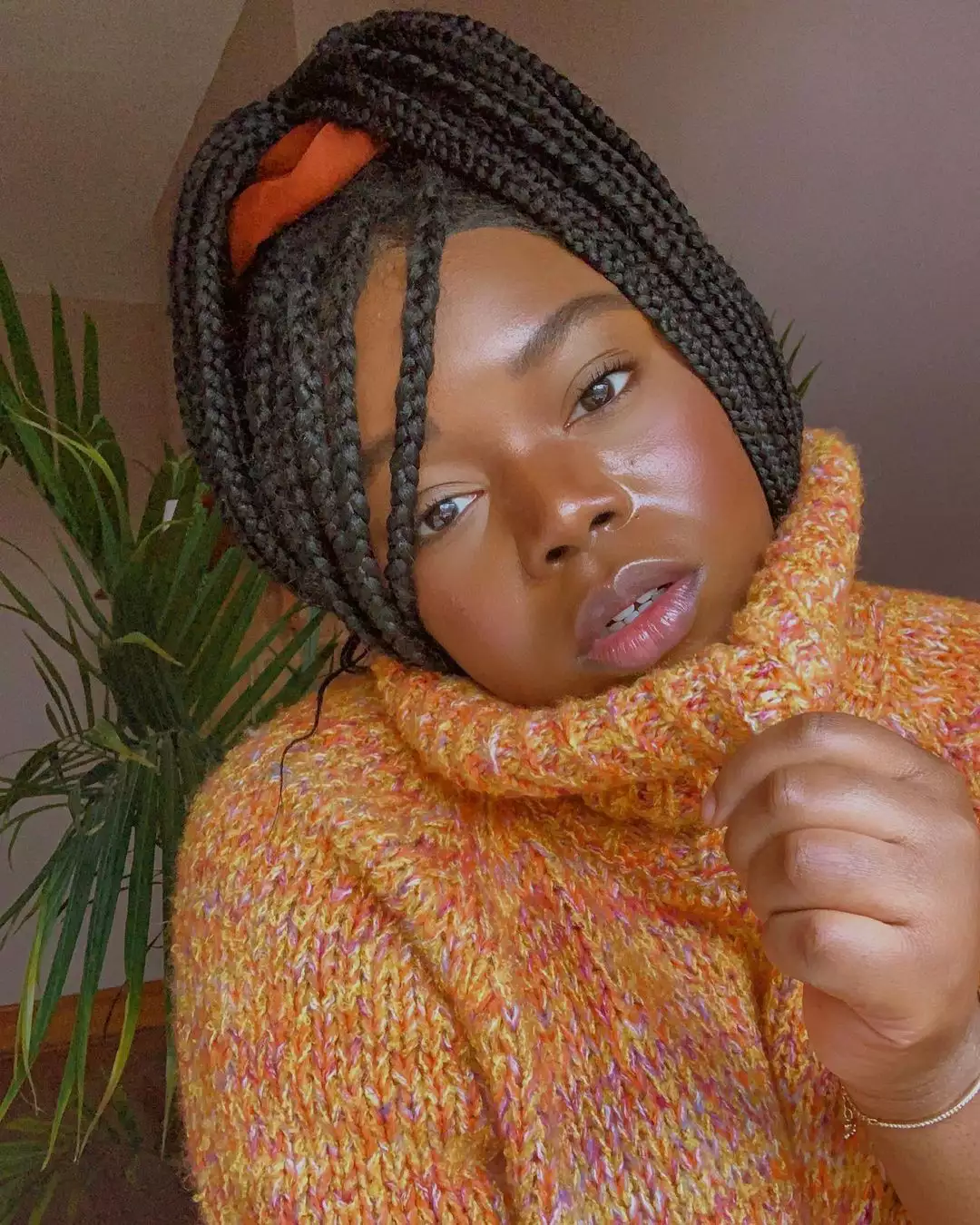 woman with no-makeup makeup in an orange turtleneck and braids