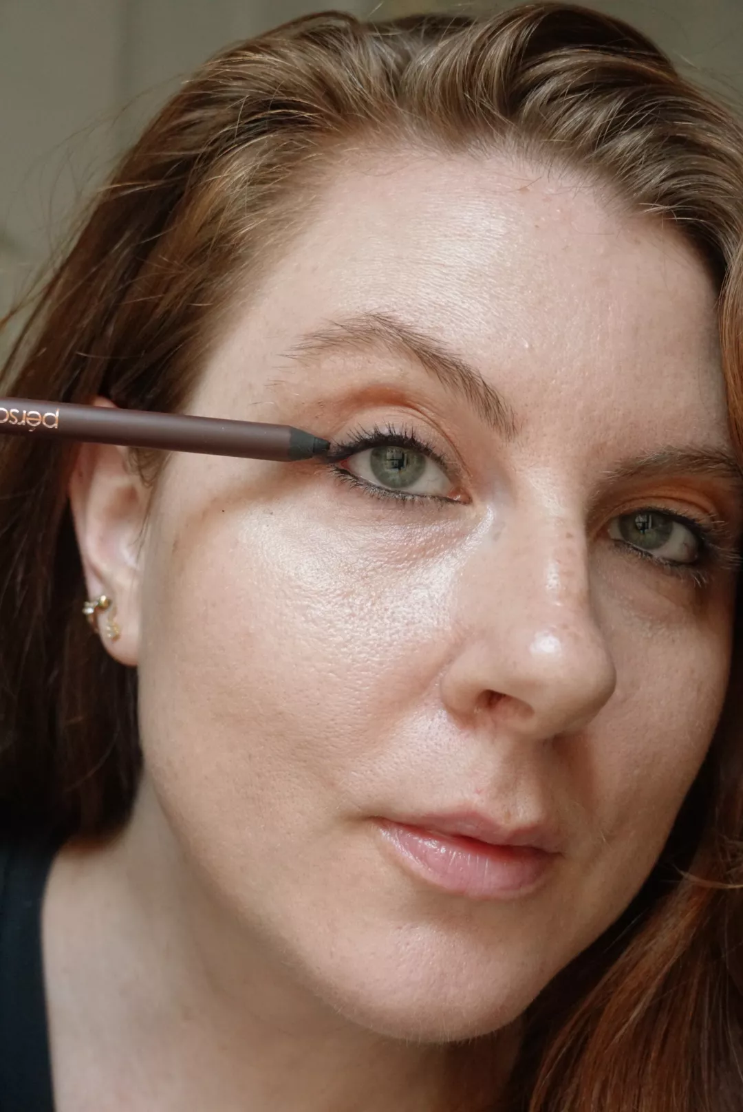 Makeup artist and Byrdie writer Ashley Rebecca applying black eyeliner to lash lines