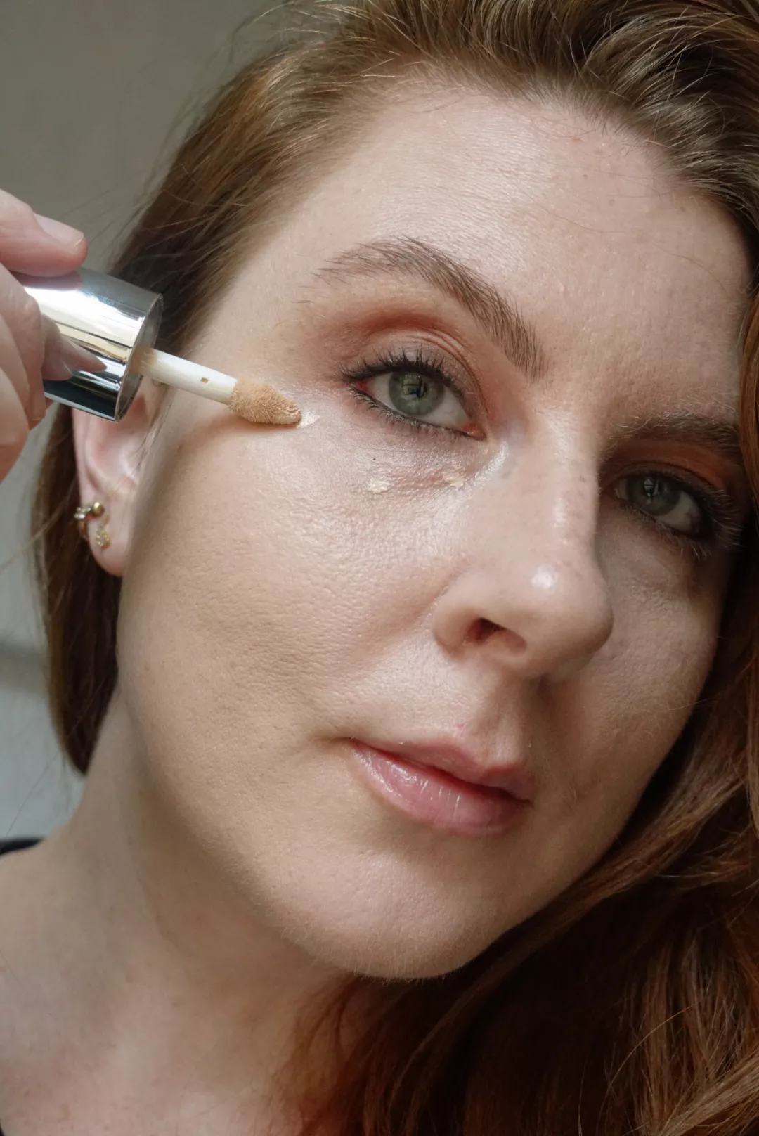 Makeup artist and Byrdie writer Ashley Rebecca applies concealer to her under-eyes