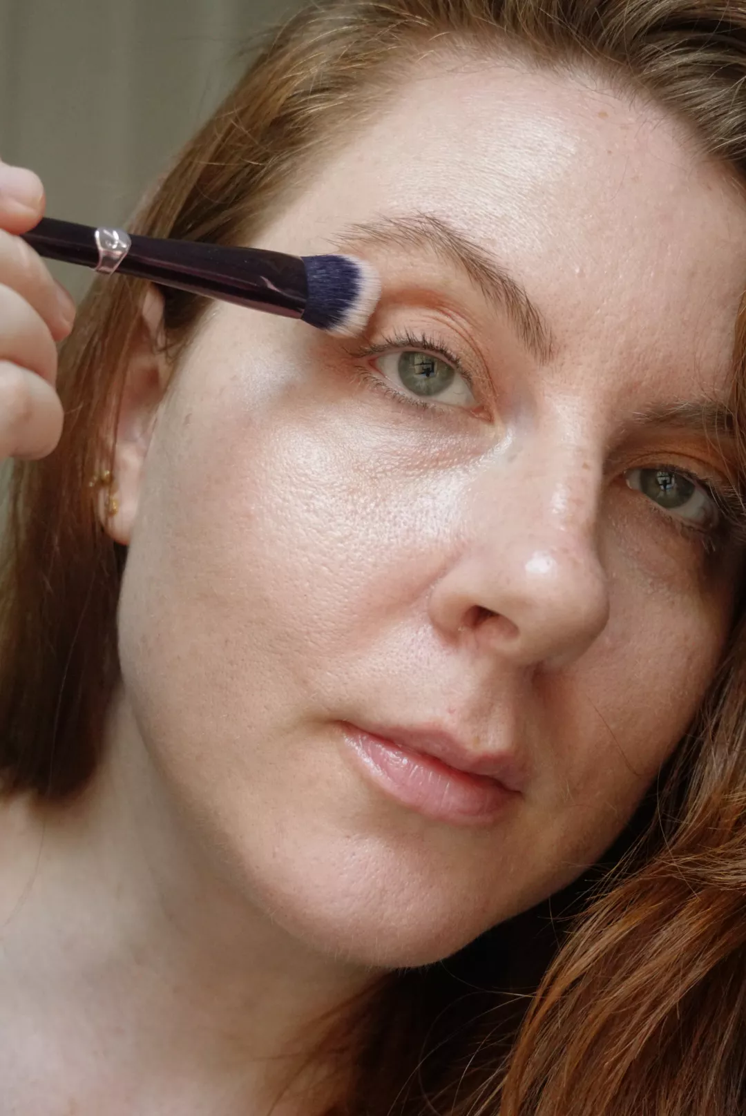 Makeup artist and Byrdie writer Ashley Rebecca applying eyeshadow to eyelid with brush