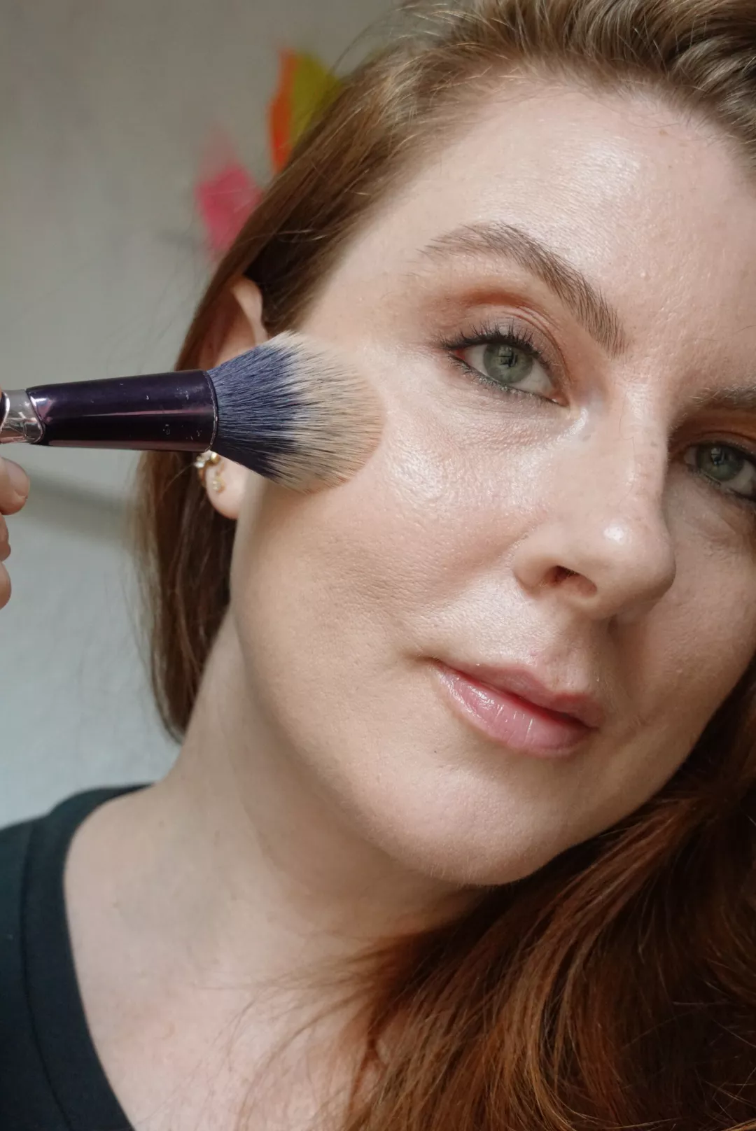 Makeup artist and Byrdie writer Ashley Rebecca applies bronzer using a fluffy brush