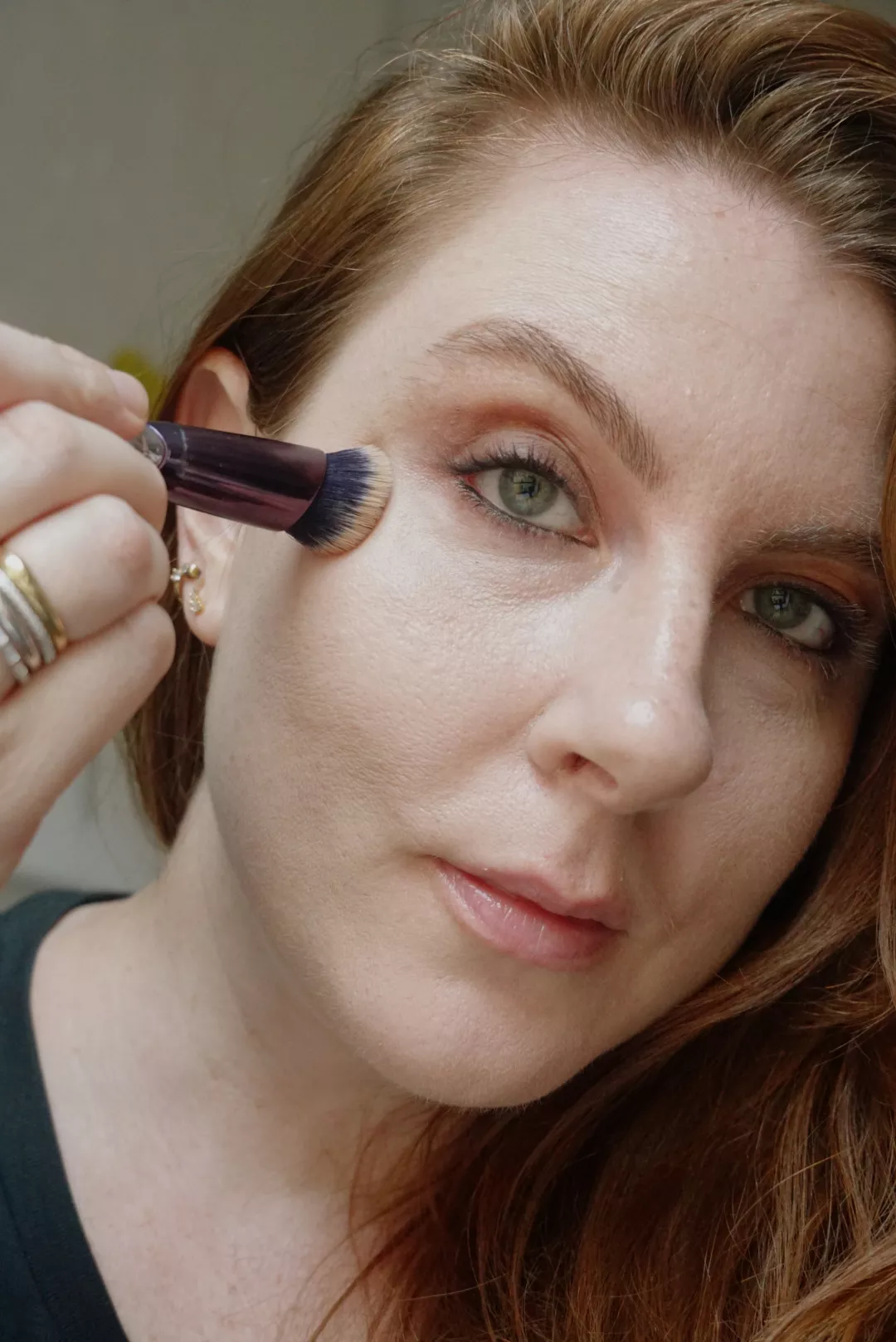 Makeup artist and Byrdie writer Ashley Rebecca blends under-eye concealer with brush