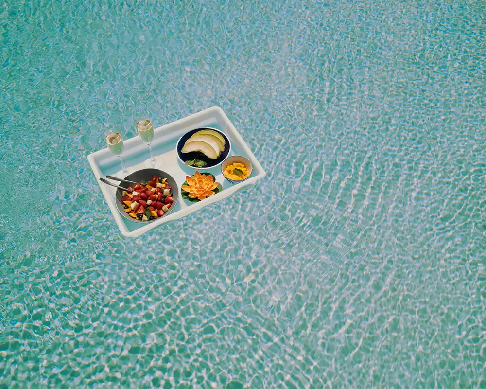 tray of fruit and champagne floating in pool