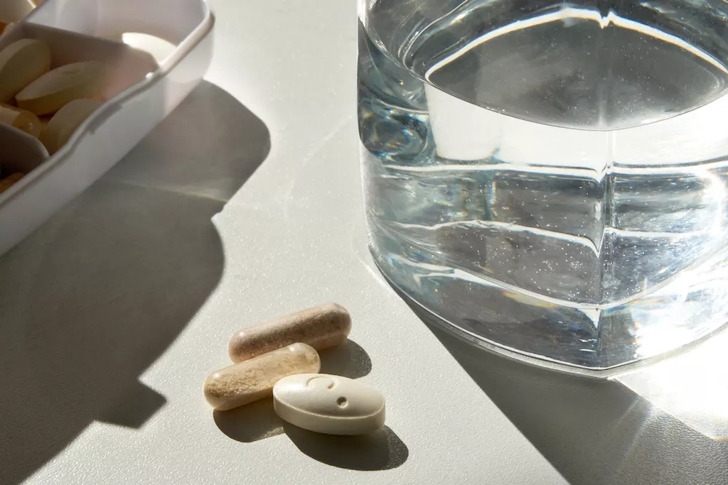 Pills on a table with a glass of water