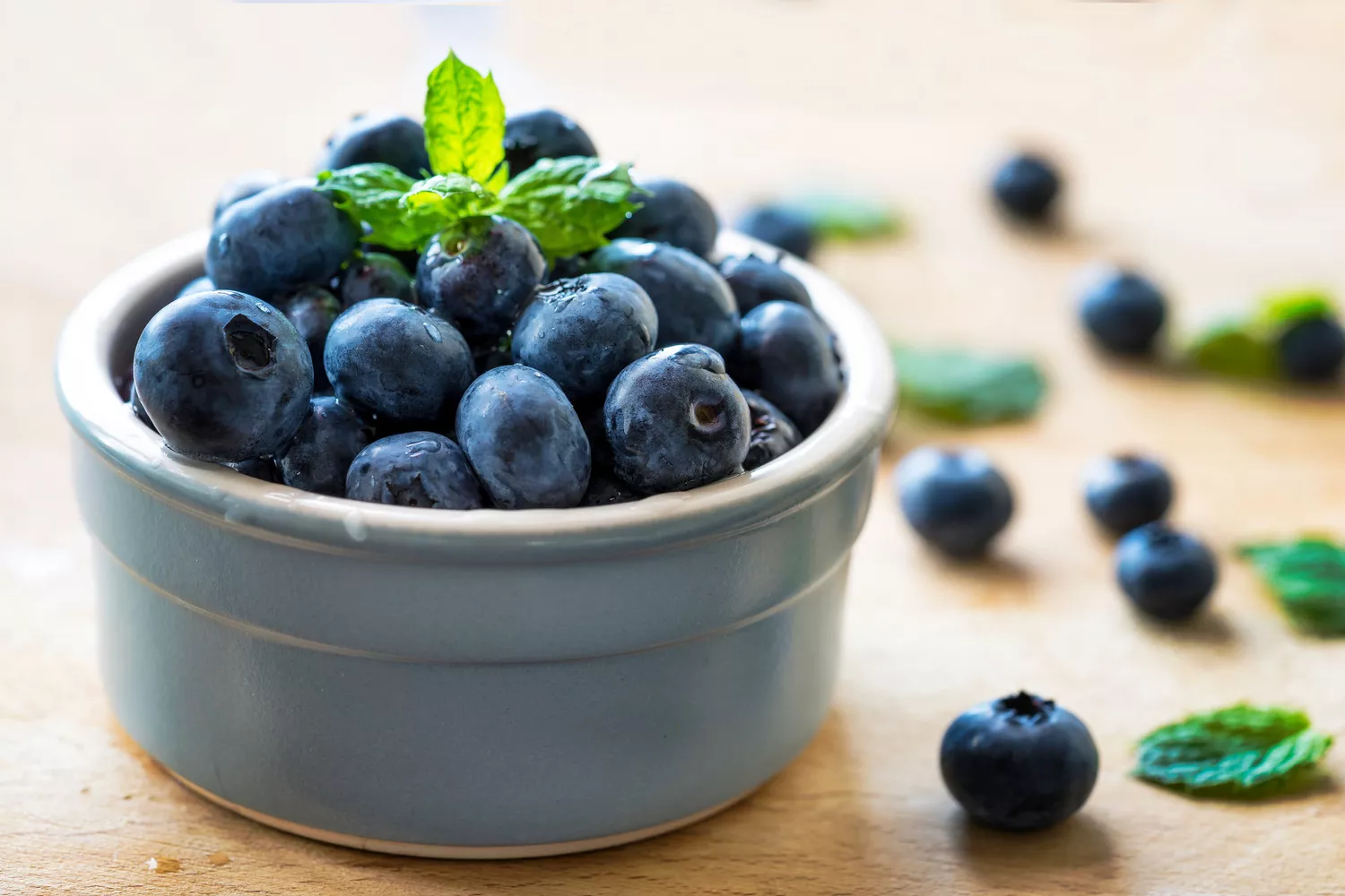 A close-up image of fresh blueberries in a bowl on a table. 