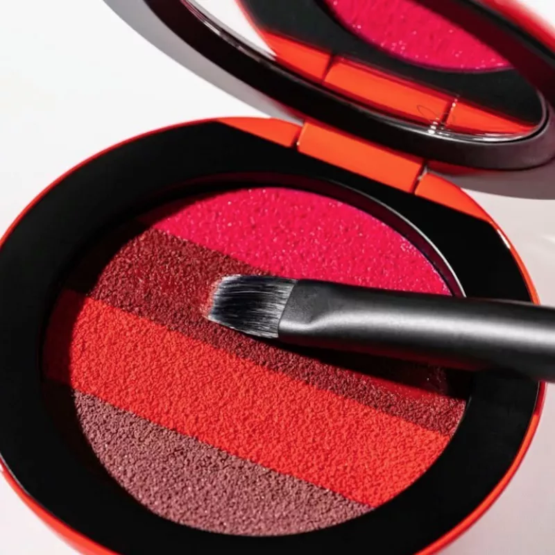Matte lipstick compact in shades of red with brush dipped in