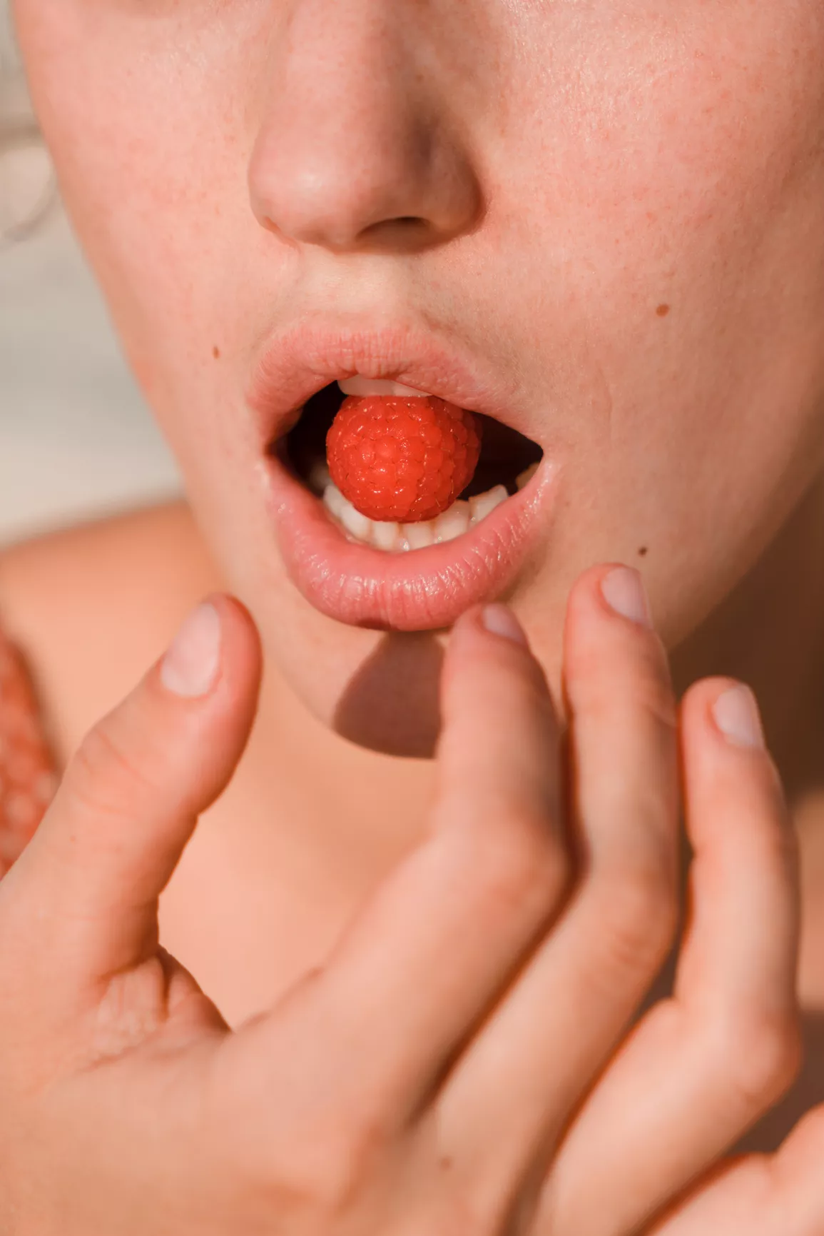 closeup of raspberry in mouth