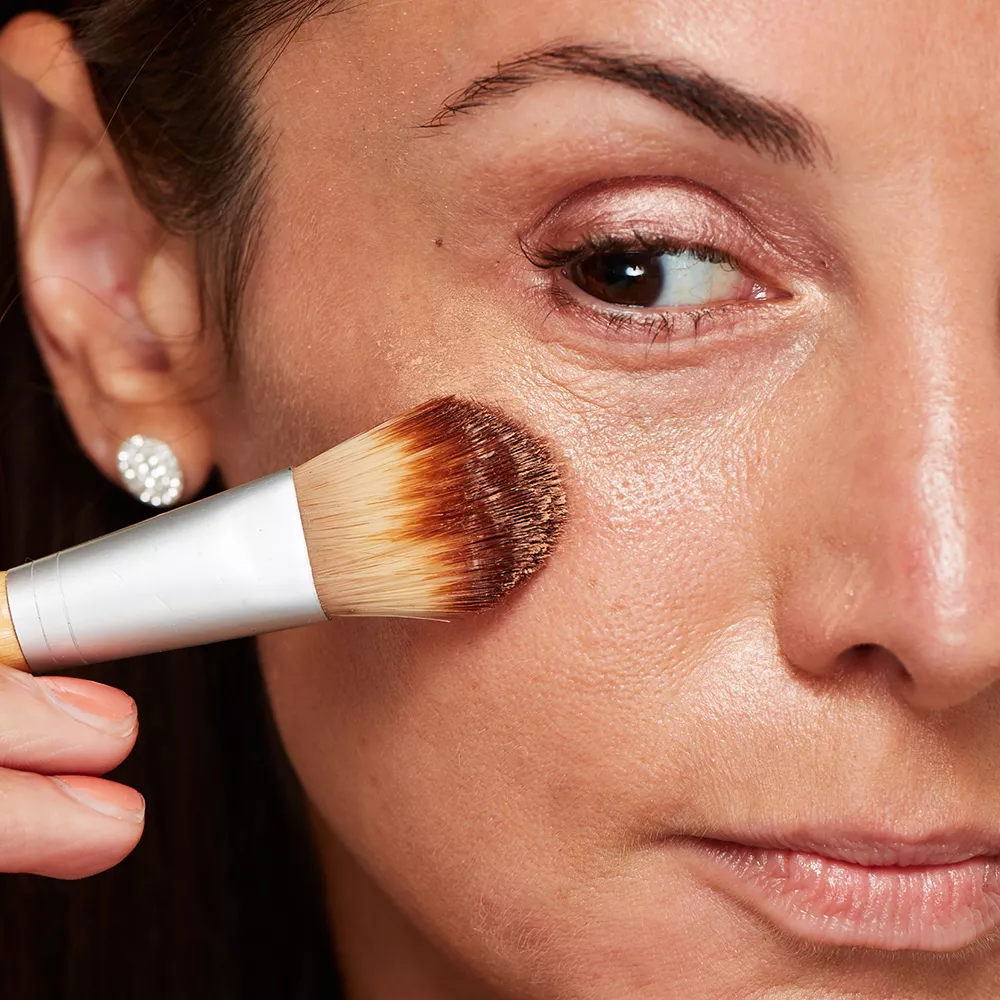 Woman with mature skin applying under eye concealer