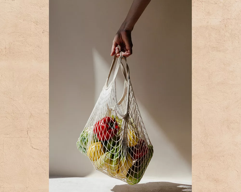 Woman holding shopping bag of fruits and veggies