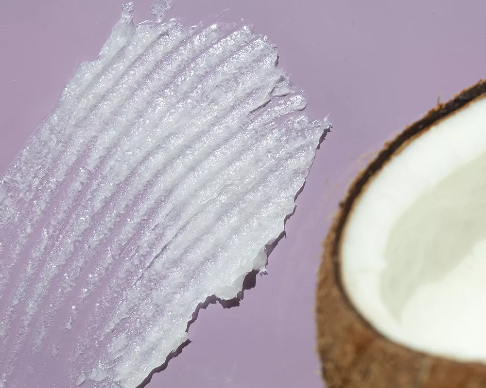 A swatch of coconut oil beside a coconut.