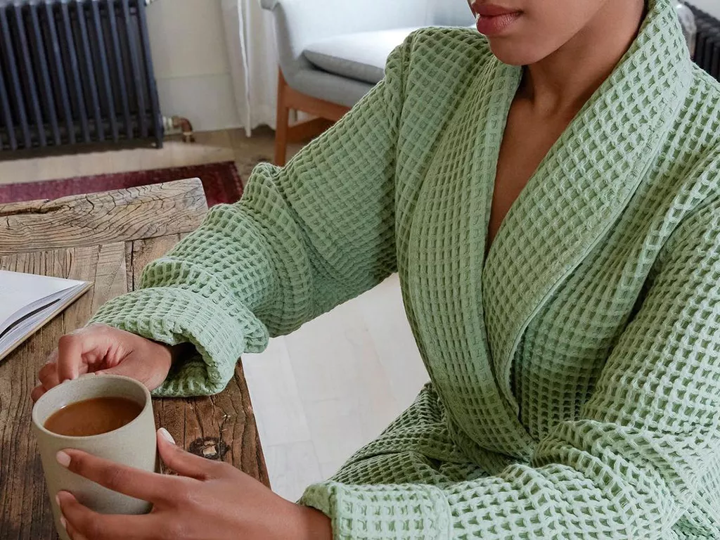 Woman sitting at the table in a robe with coffee and an open book