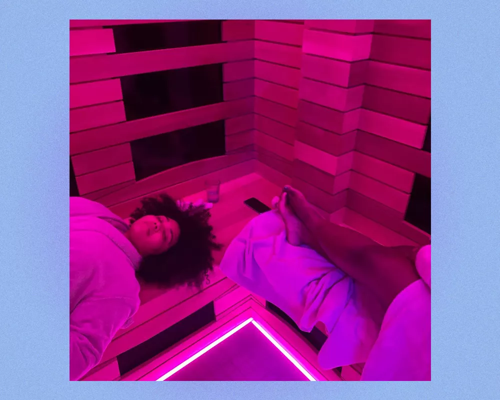 Women lounge in a sauna, with purple infrared lighting