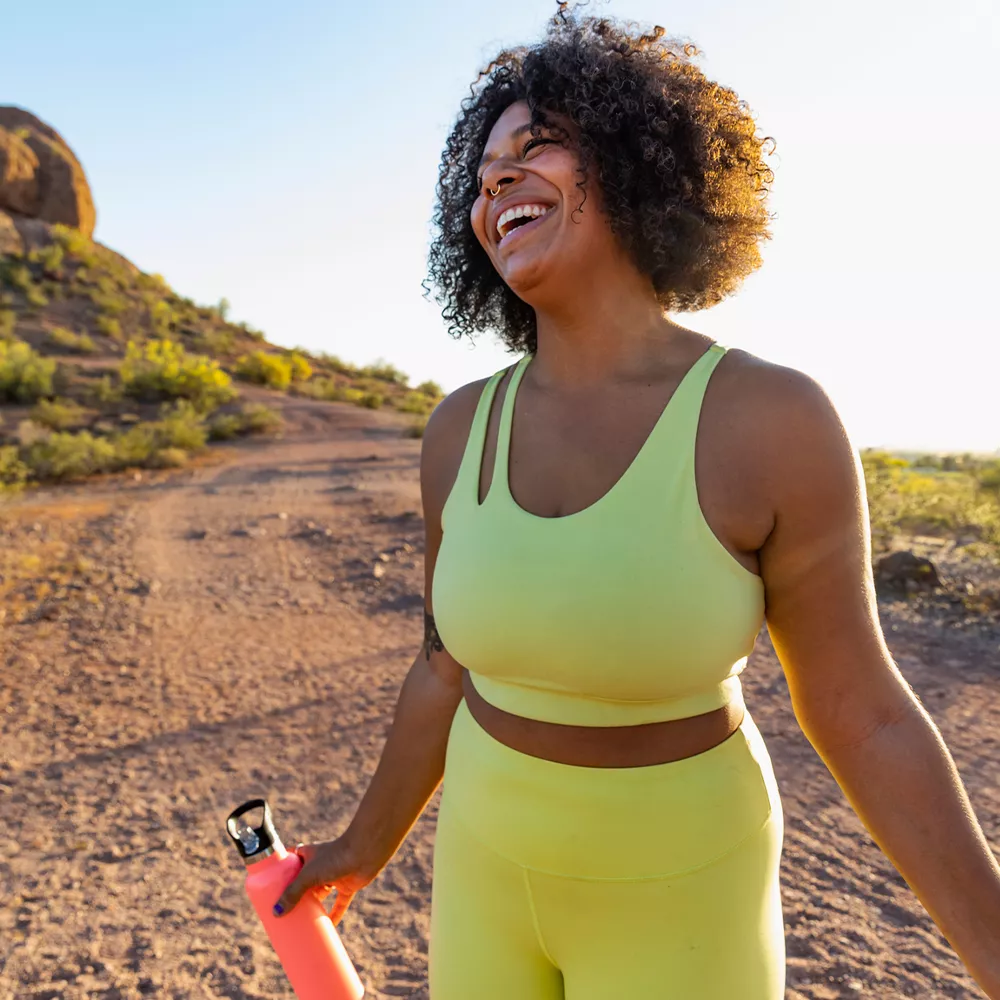 woman smiling and hiking in yellow activewear set