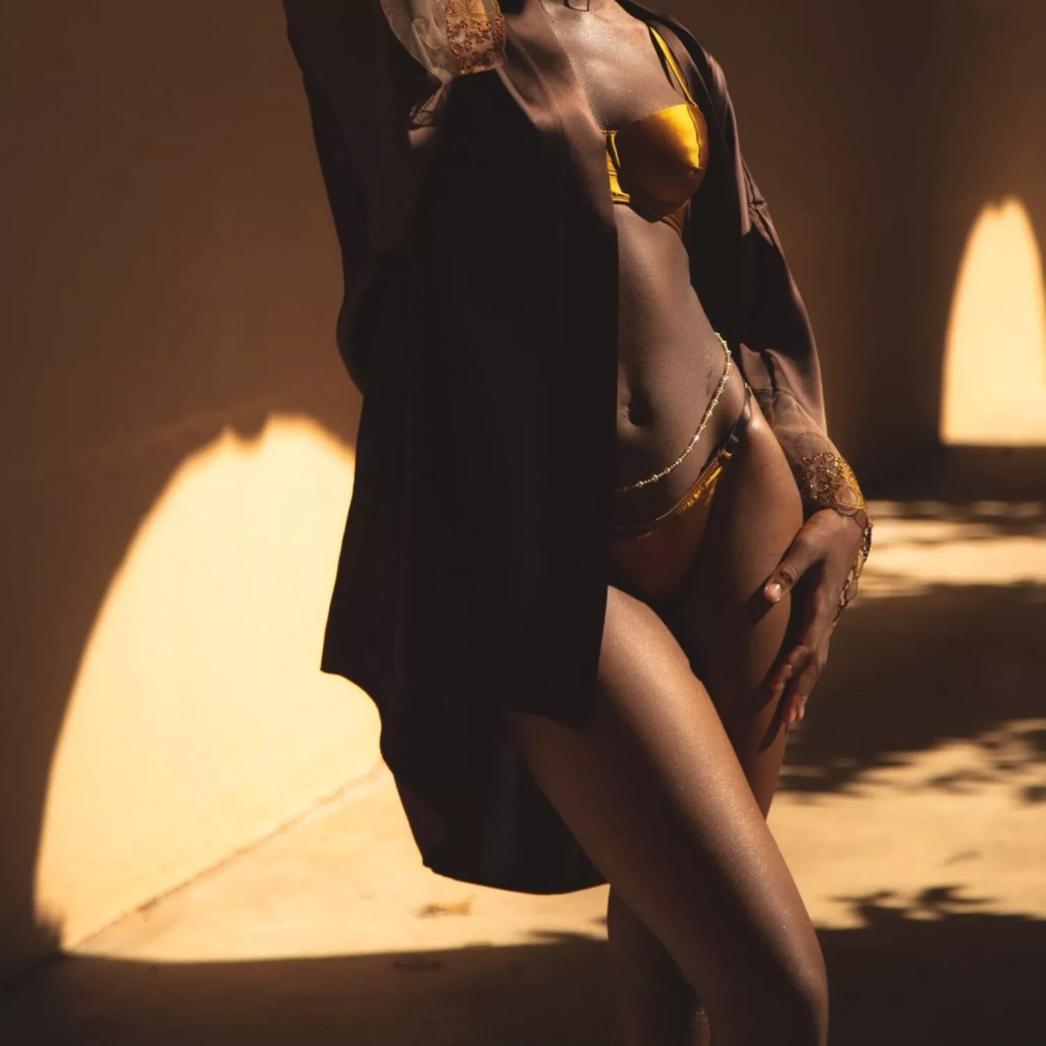 Model wears gold lingerie set and dark brown robe