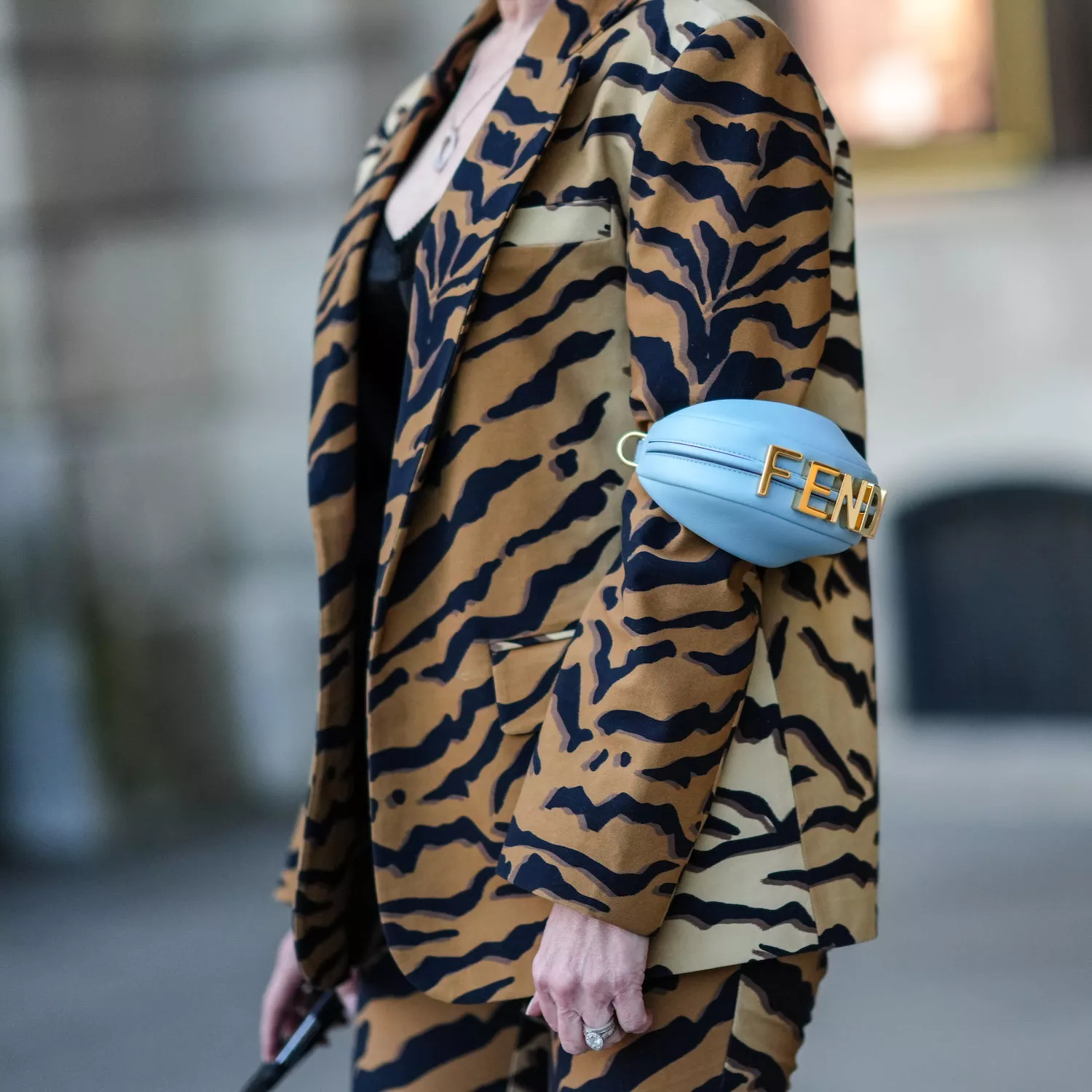 Close-up of woman wearing tiger print suit and baby blue Fendi bracelet bag
