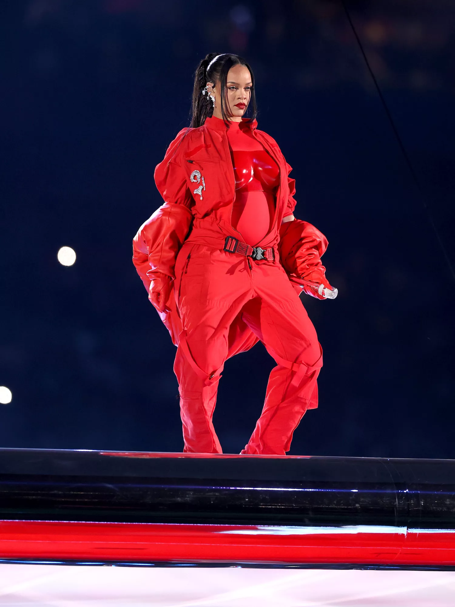Rihanna wears a red jumpsuit and bodysuit on stage at the Super Bowl LVII halftime show