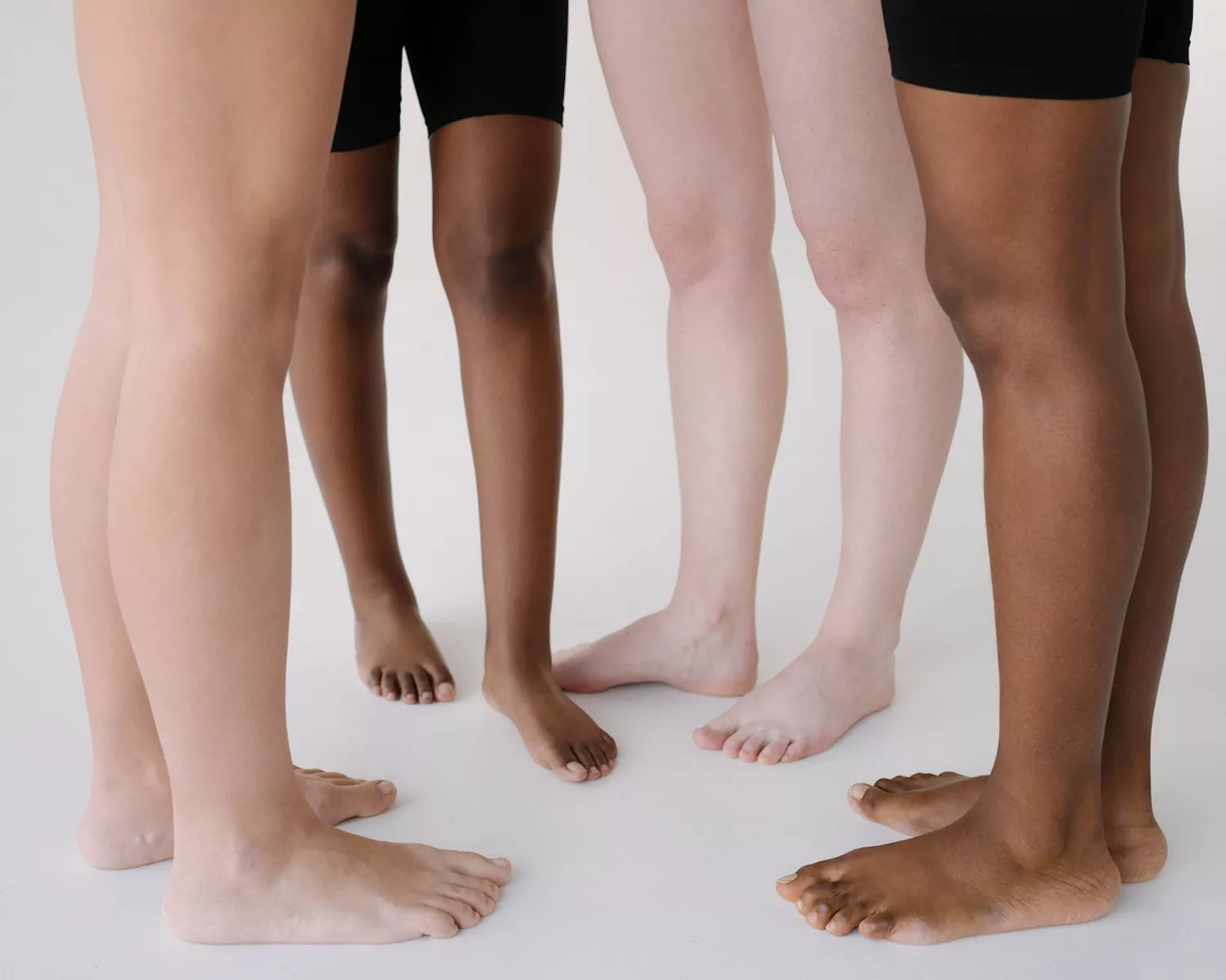 Close up of legs of four women with various skin tones and body types