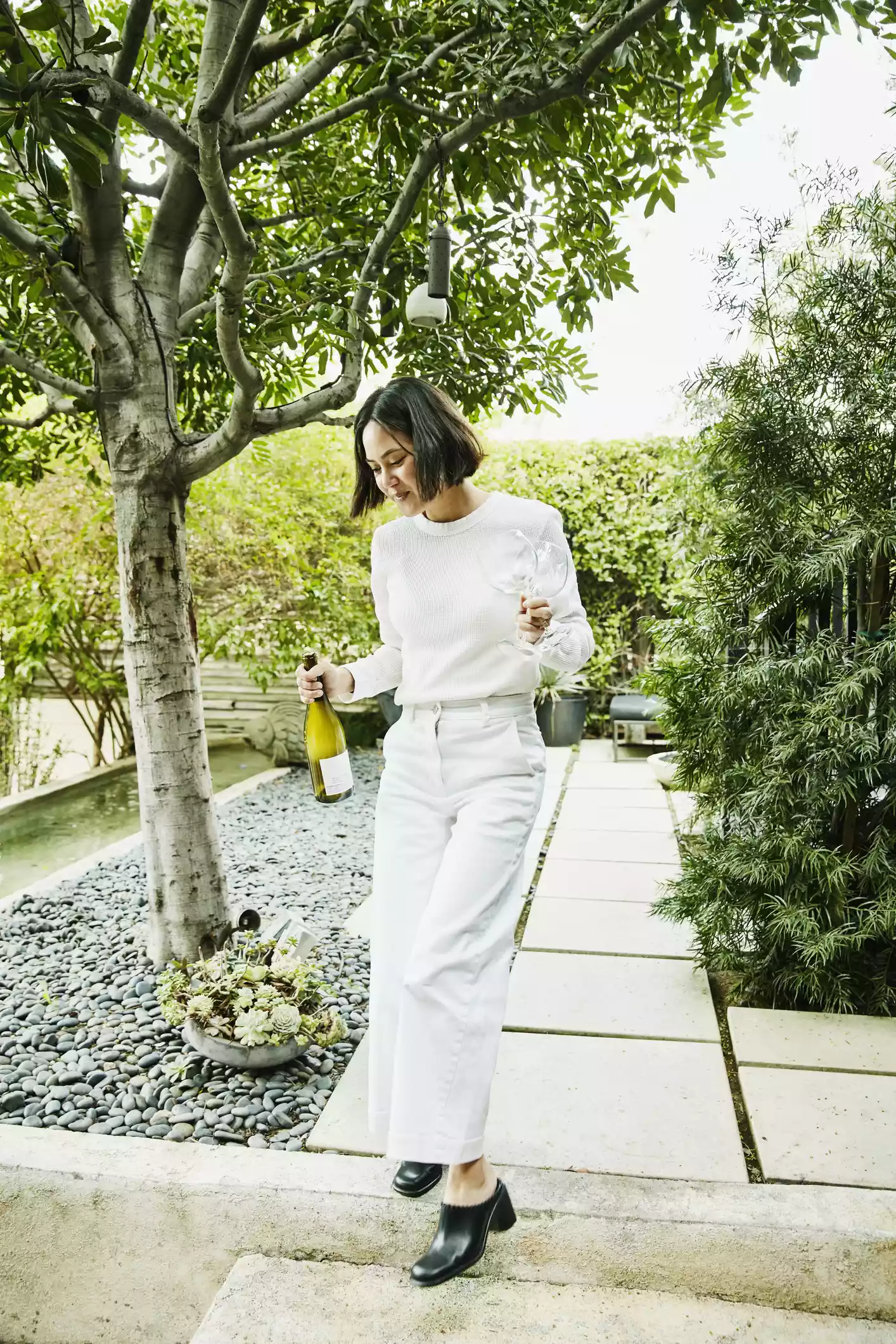 Woman holding wine wearing white jeans