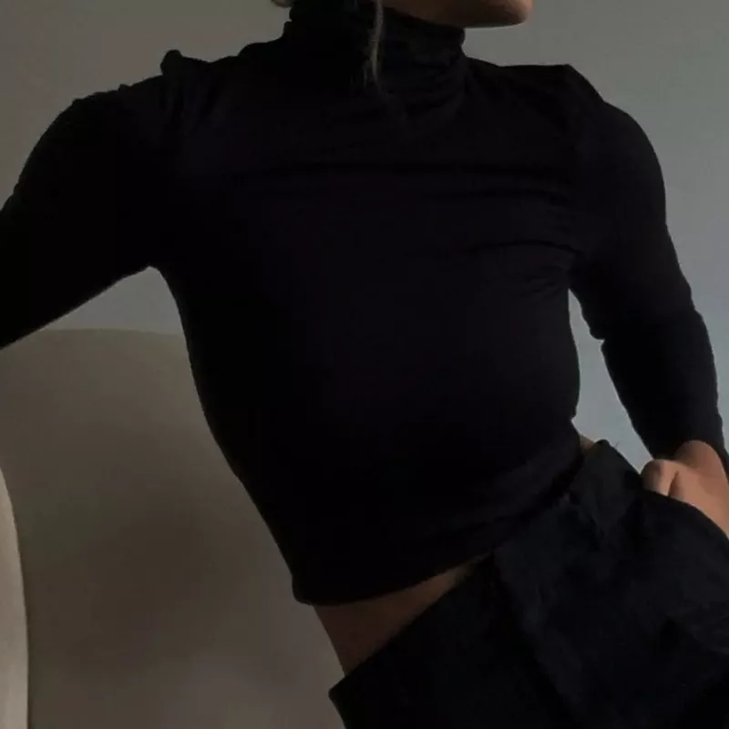 Model wears black turtleneck and simple black pants
