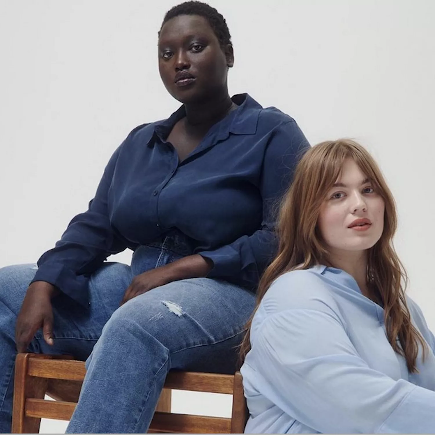 Women wearing blue button-down blouses and jeans on a white background