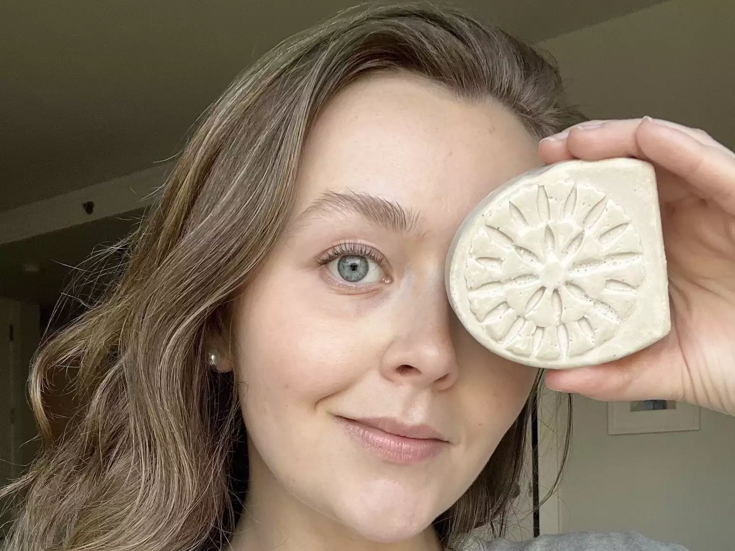 woman holding lush face soap bar up to face
