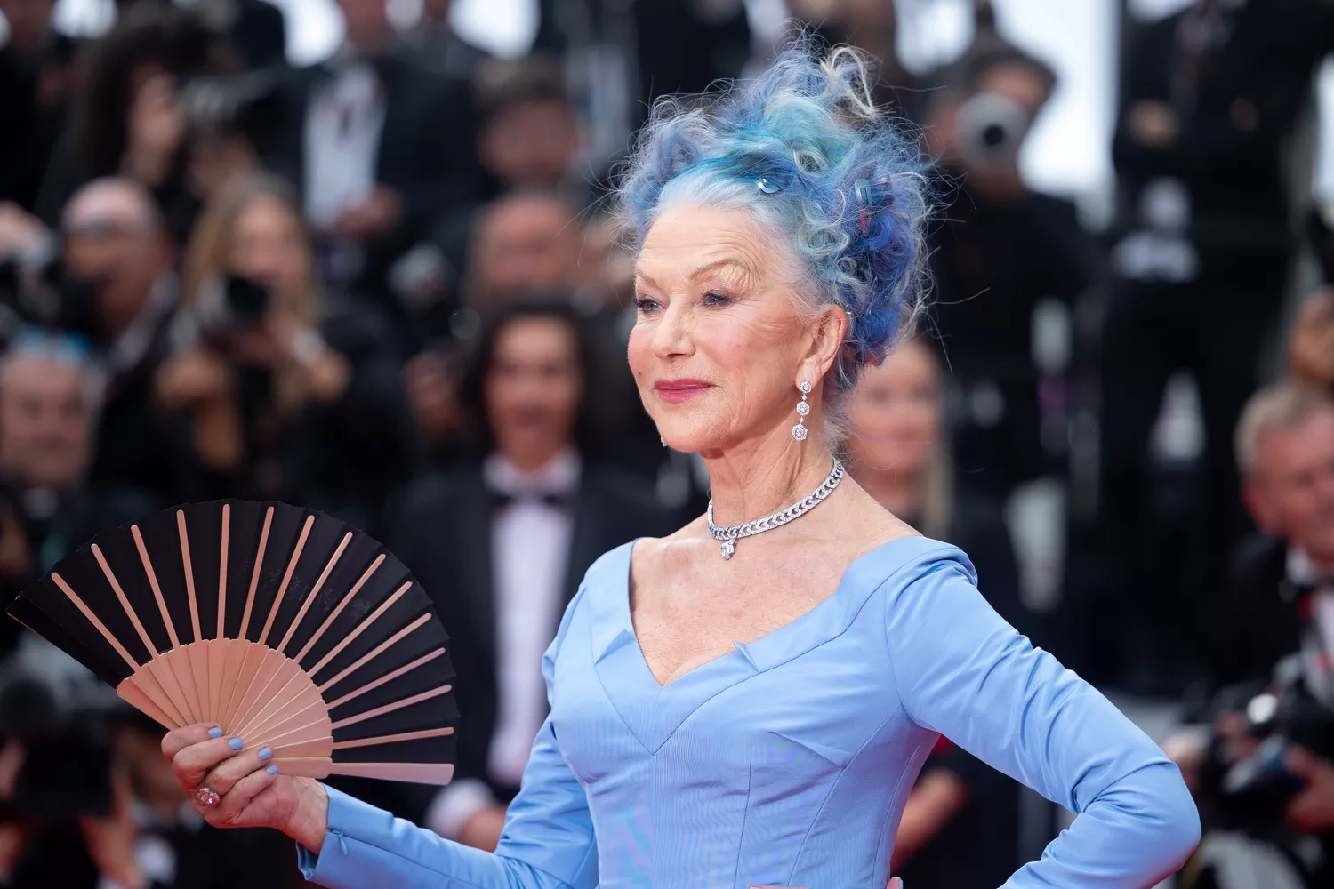 Helen Mirren holding fan at the 2023 Cannes film festival in blue gown and hair