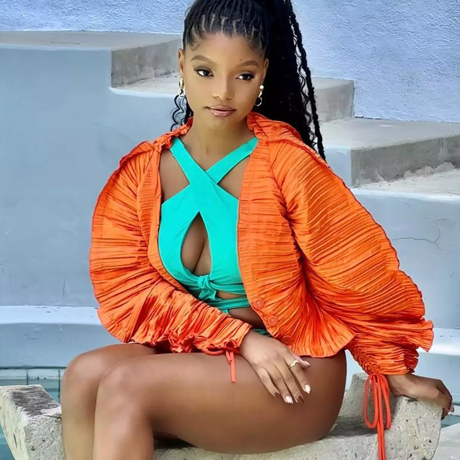 Halle Bailey wearing a blue swimsuit and brown and white nails 