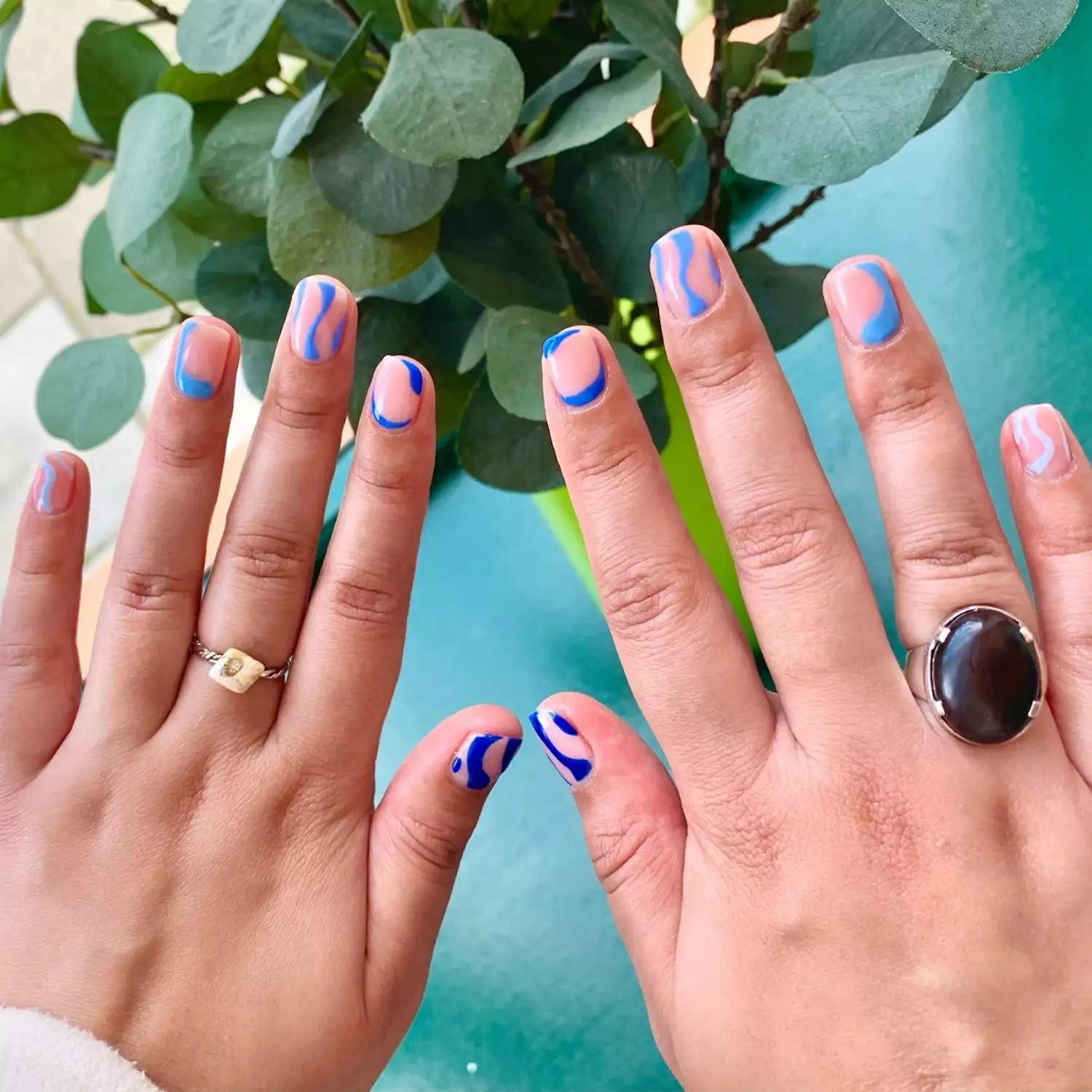 Manicure with abstract wavy designs in various shades of blue