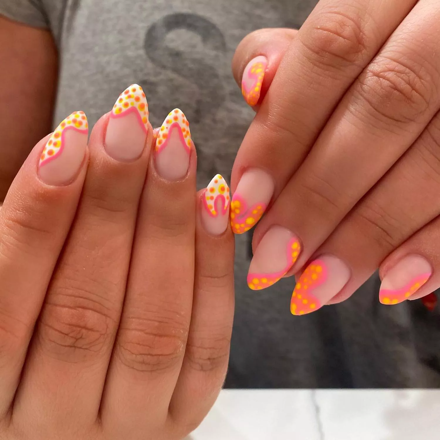 Almond-shaped manicure with pink, yellow, and white wavy bubble dot design