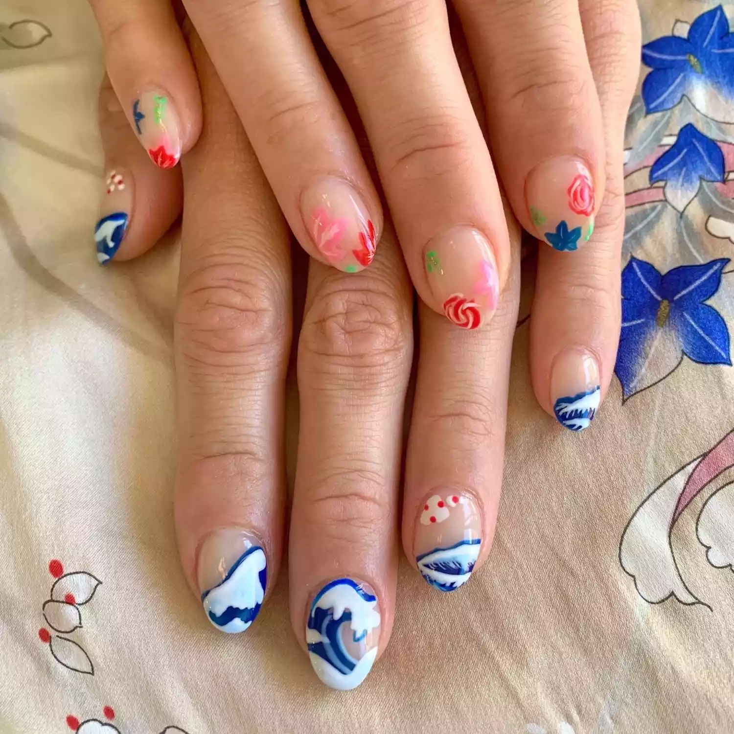 Manicure with one hand of Hokusai wave designs and one hand of island floral designs