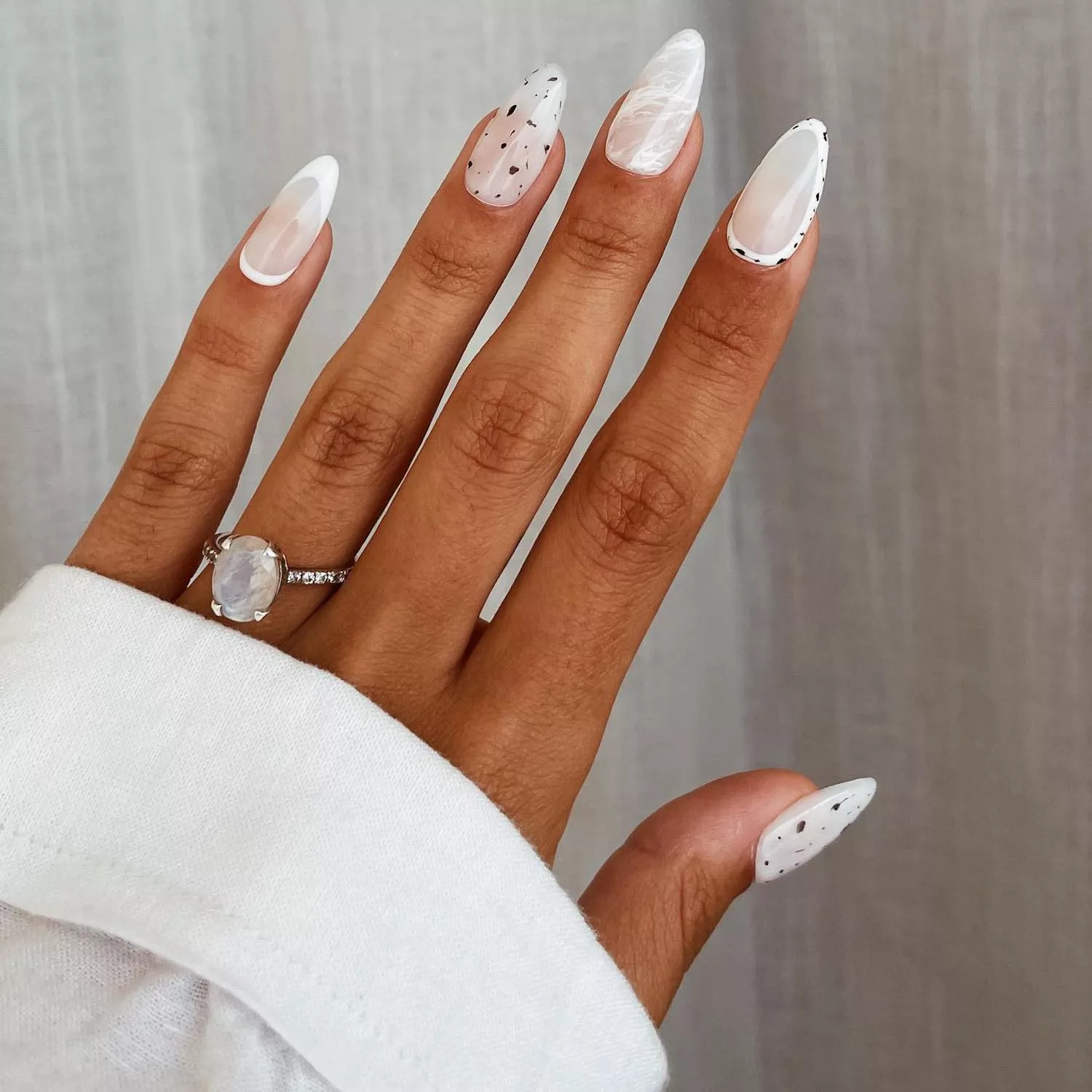 White glazed manicure with soft speckling, marbling, and solid white and speckled cuticle details