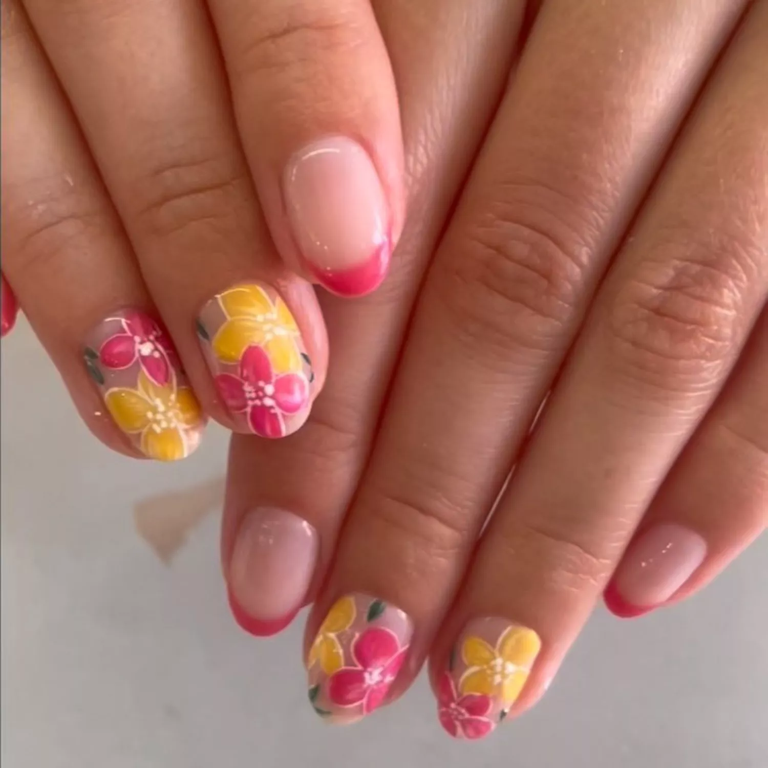 Manicure with pink French tips and pink and yellow floral designs