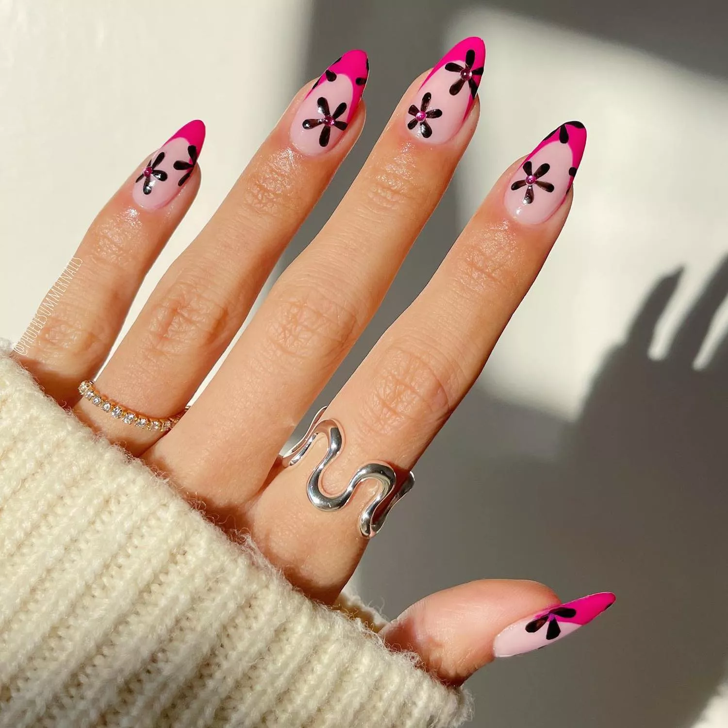 Manicure with hot pink French tips and black floral design with pink rhinestones